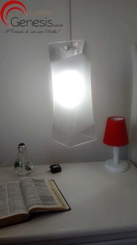Luminária de teto pendente de vidro quadrado torcido, iluminando uma mesa com livro aberto e abajur vermelho. Lustres Gênesis loja online de Lustres e Iluminação Decorativa